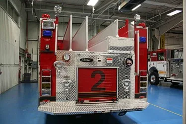 Straight rear view showing rear roll-up door, hosebed dividers, warning lights, and tailboard.