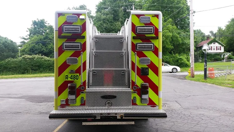 Straight rear view with red-yellow chevrons, rear access panel, and upper hosebed divider section.