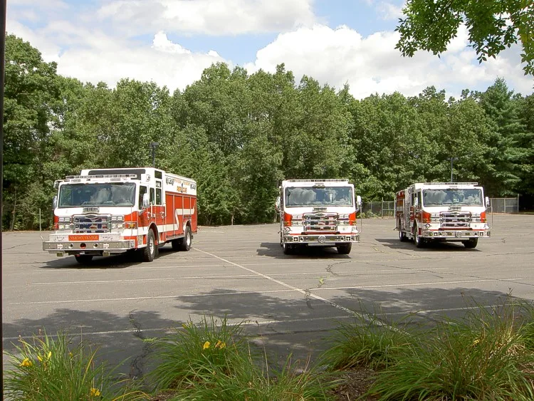 Front view of parked pumper lineup with grassy area in foreground