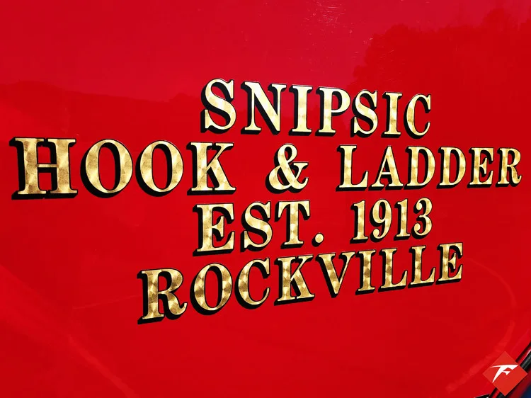 Body panel close-up showing gold company lettering on red paint