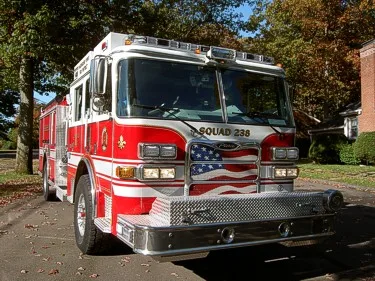 Front-left close view highlighting the grille, bumper, windshield, and warning lights.