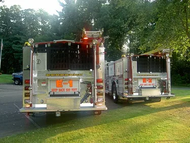 Rear view of two pumpers showing hosebed openings and rear warning lights