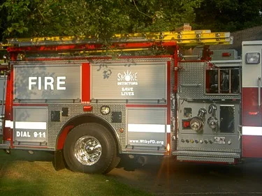 Driver-side mid-body close-up showing side compartments, rear wheel, and ladders