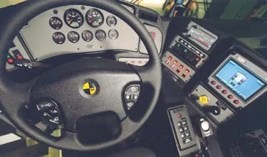 Driver cockpit close-up showing steering wheel, gauges, and control console