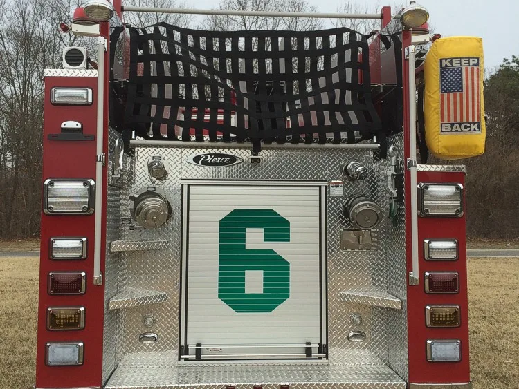 Rear close-up showing hosebed netting, rear intake connections, and center rear compartment door.