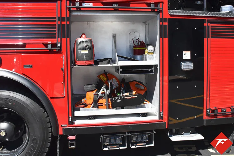 Open lower compartment showing chainsaw and tools near rear wheel