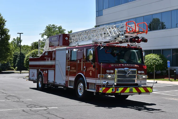 Front-left profile showing tower ladder body, bumper, and side compartments