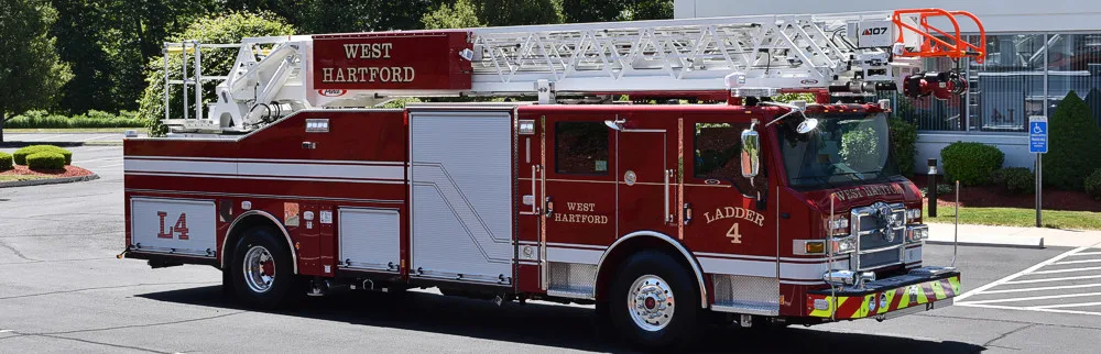 Tower ladder truck side profile view parked in lot with closed compartments