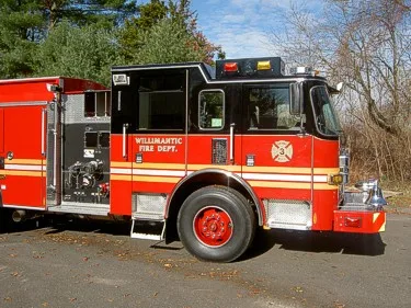 Left-side mid-cab view with door area, front wheel, and pump controls behind the cab.