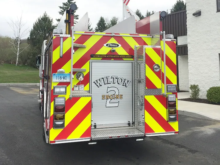 Straight rear view with red-yellow chevrons, rear roll-up door, and tail light stacks.