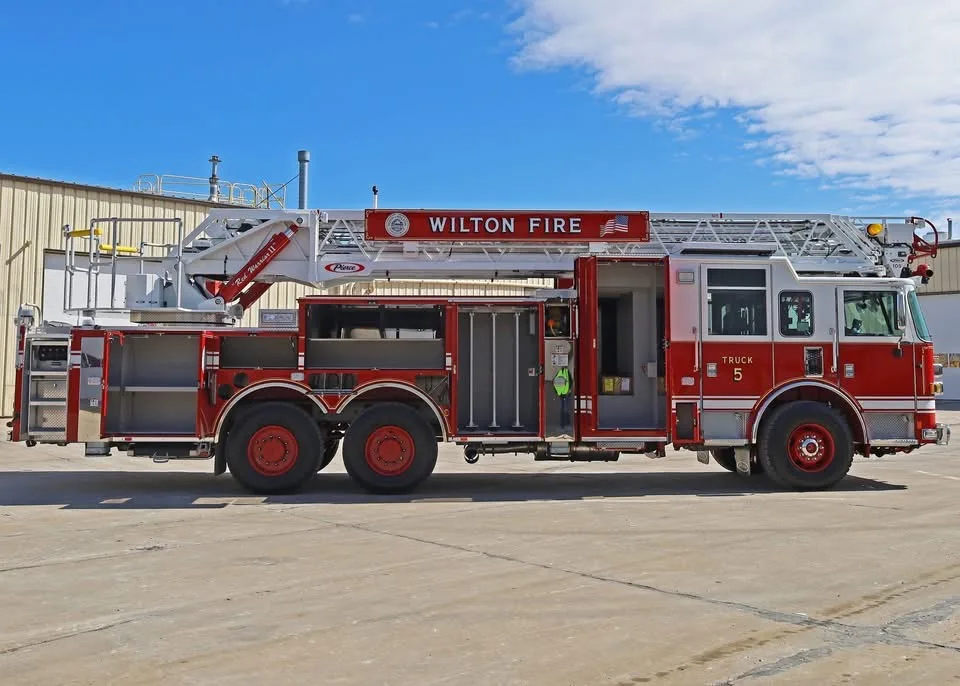 Driver-side full profile showing tower ladder body and tandem rear axles