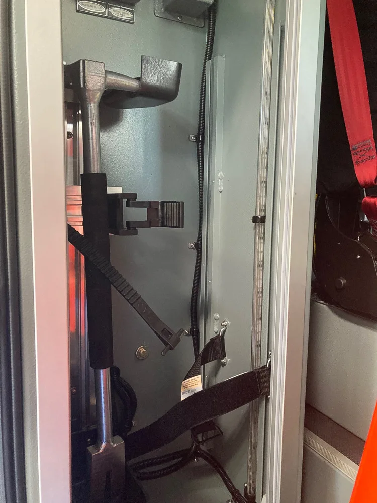 Open narrow side compartment showing mounted long tools and clamps