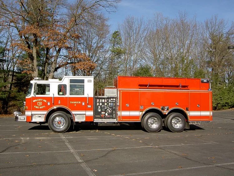 Driver-side full profile with pump panel controls, side ladder rack, and tandem rear wheels.