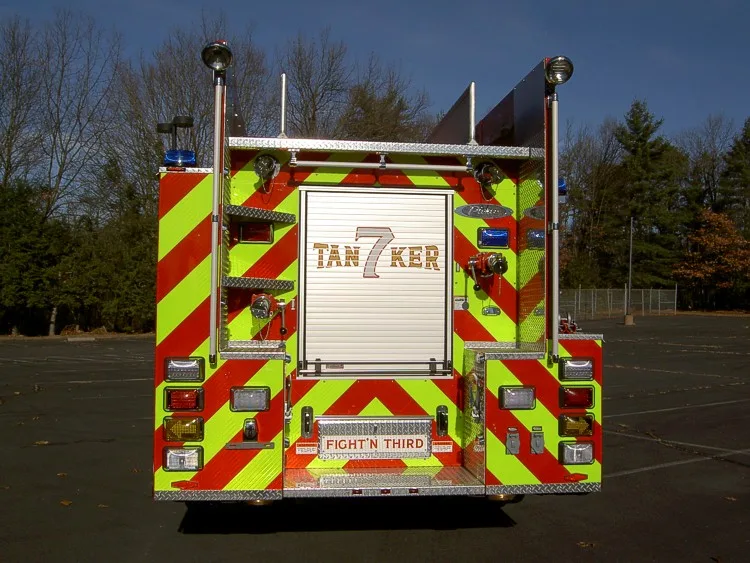 Straight rear view with red-yellow chevrons, rear discharge area, and center rear roll-up door.