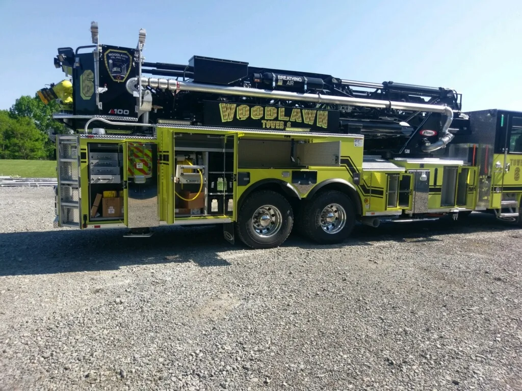 Driver-side mid-body view showing open compartments and tandem axles