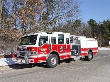 Front left wide view showing the full apparatus length, midship pump panel area, and rear body compartments.