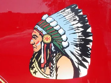 Close-up of a side body logo panel showing a profile emblem on red paint.