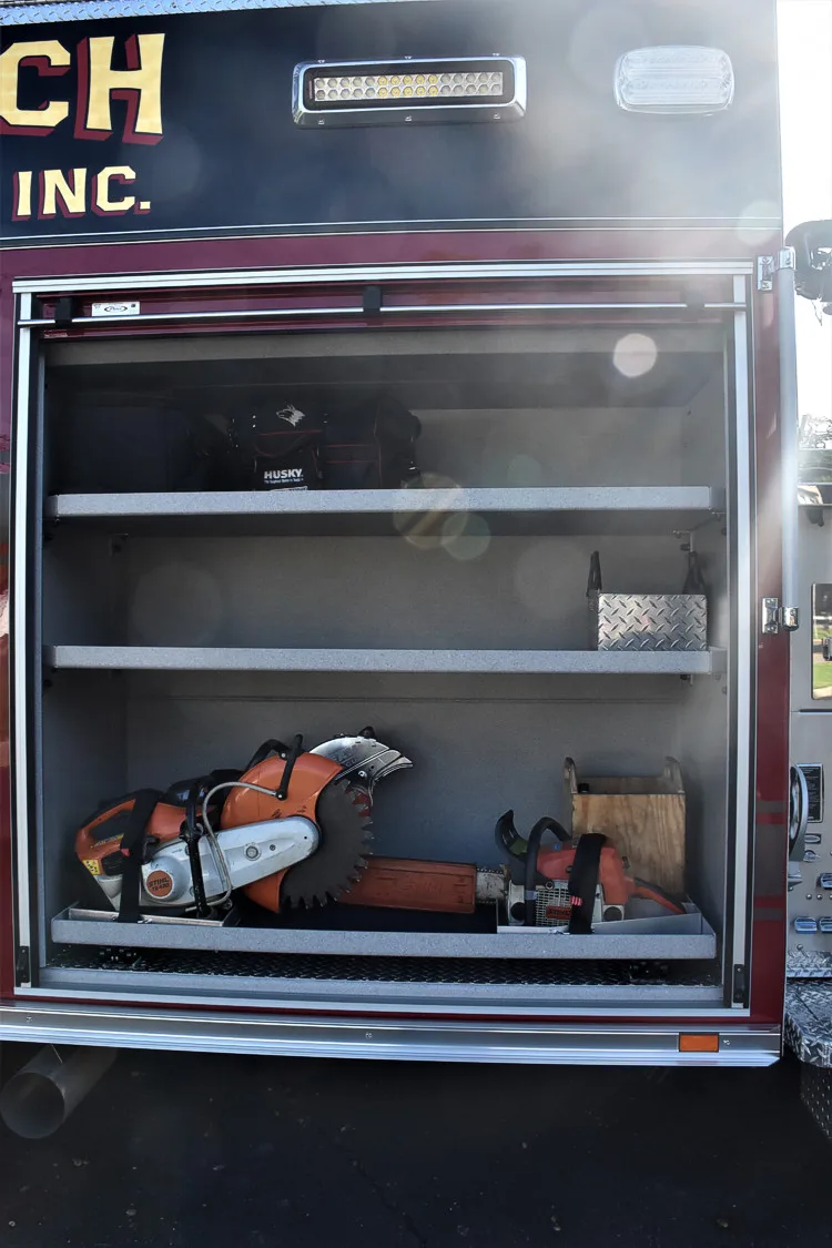 Open side compartment showing shelf storage with saws and equipment
