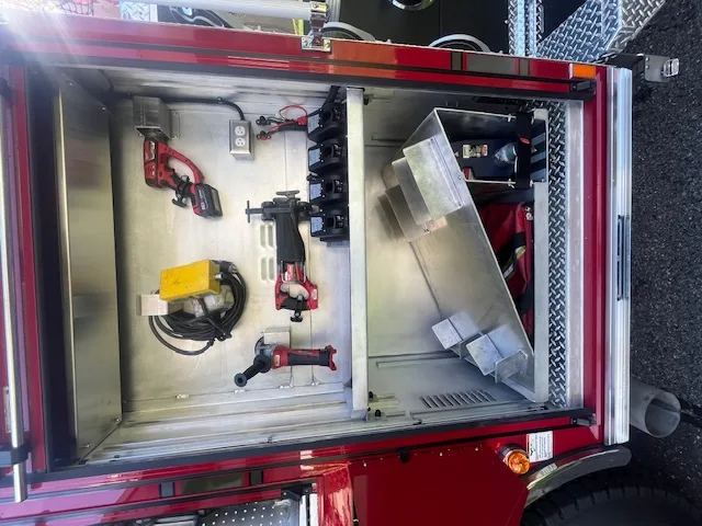 Open equipment compartment showing mounted cordless rescue tools and chargers