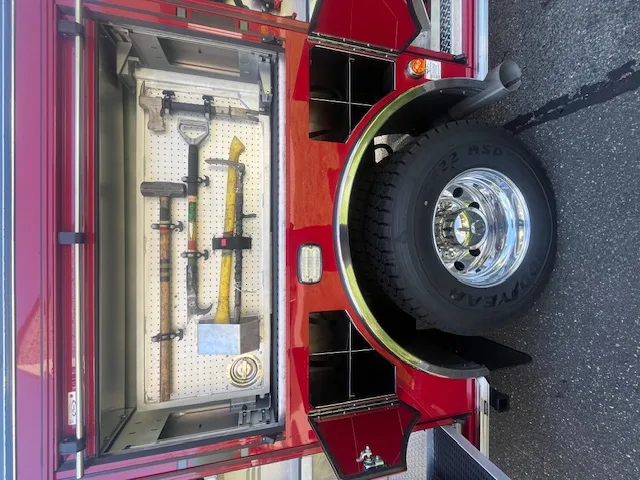 Open side compartment with mounted hand tools beside rear wheel and tire