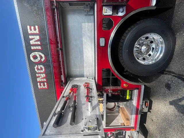 Open side compartment with mounted hand tools, rear wheel, and lower storage bay