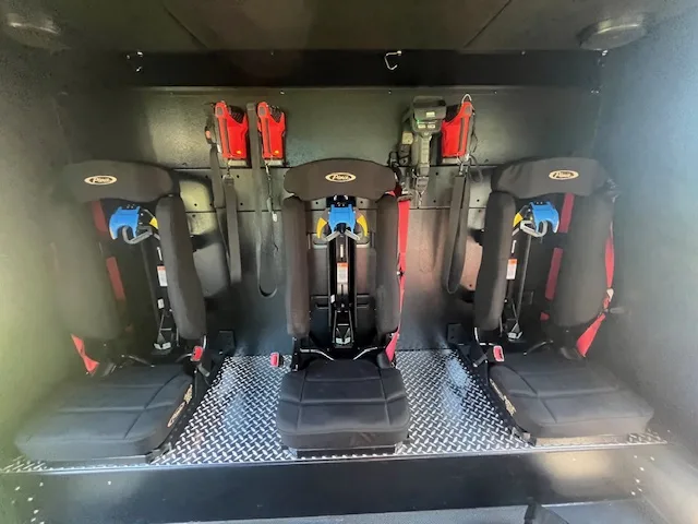 Rear crew compartment interior close-up showing fold-down seats and SCBA mounts