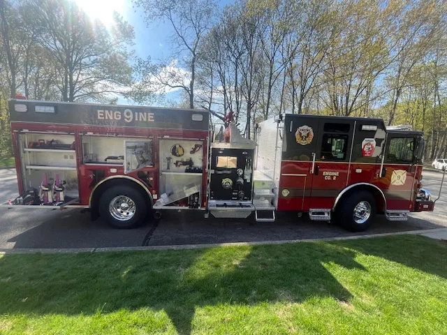 Pierce Enforcer top-mount pumper, driver-side profile with open compartments and equipment storage