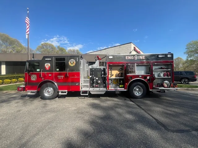 Pierce Enforcer top-mount pumper, officer-side profile with open compartments and visible pump panel